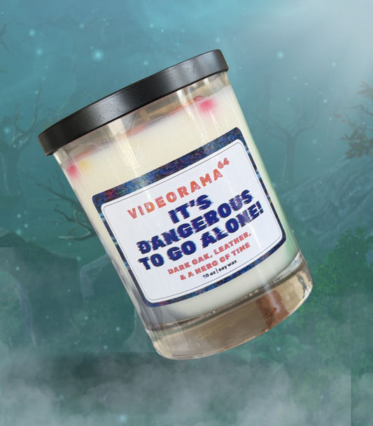 Videorama64 "It's Dangerous to Go Alone" Zelda-inspired soy candle, 10 oz, dark oak and leather scent, glitch-style label, misty forest background